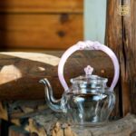 transparent glass teapot with pink flower basket handle